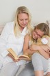 © lightwavemedia - Mother and daughter reading story book in bed