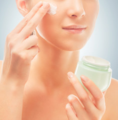 Poster - Woman applies cream on face, close-up