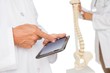© WavebreakMediaMicro - Mid section of doctors with digital table and skeleton model