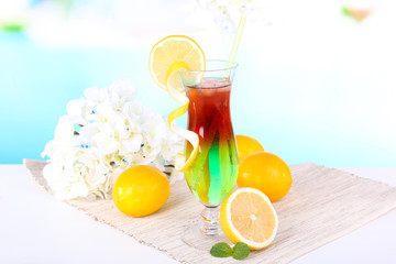 Poster - Glass of cocktail on table on light blue background