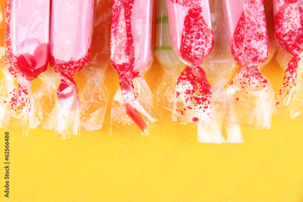 Tasty candies on yellow background