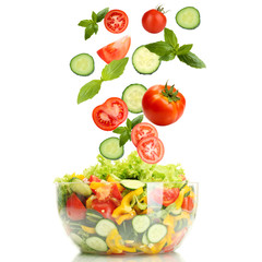 Fresh mixed vegetables falling into bowl of salad isolated