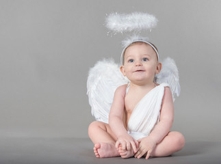 Smiling infant with angel wings and nimbus on neutral background