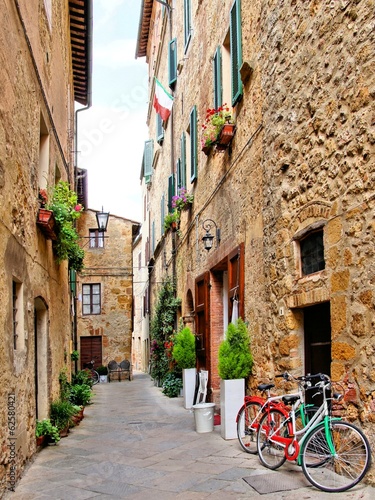 Nowoczesny obraz na płótnie Narrow small town lane in Pienza, Tuscany, Italy with bikes