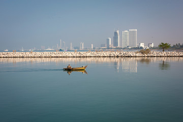 Fisherman in a boat at sea with urban landscape