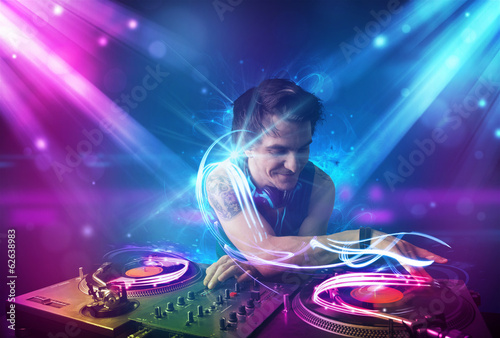 Plakat na papierze fotorealistycznym Energiczny dj miksujący muzykę z potężnymi efektami świetlnymi