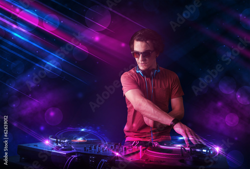 Plakat na papierze fotorealistycznym Młody dj grający na gramofonach z kolorowymi efektami świetlnymi