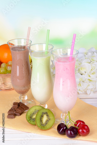 Naklejka - mata magnetyczna na lodówkę Milk shakes with fruits on table on light blue background