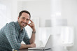 © Mint Images - Office Interior. A Man Seated At A Table, Using A Laptop Computer.