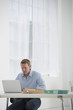 © Mint Images - Business. A Man Sitting At A Desk Using A Laptop.