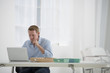 © Mint Images - Business. A Man Sitting At A Desk Using A Laptop.