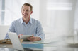 © Mint Images - Business. A Light Airy Office Environment. A Man Sitting Holding A Digital Tablet.