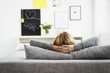 © Westend61 - Germany, Bavaria, Munich, Young woman relaxing on couch