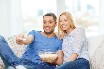 Canvas Print - smiling couple with popcorn watching movie at home