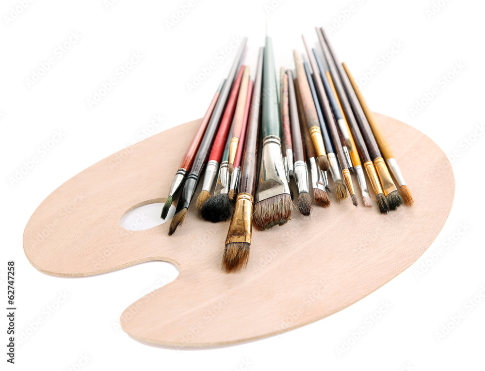 Many brushes on wooden palette, isolated on white