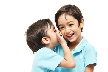 Wall Mural - Little sibling boys sharing a secret on white background