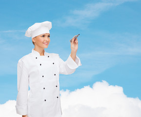 Canvas Print - smiling female chef writing something on air