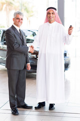 Wall Mural - senior car salesman handshake with Arabic customer