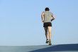 © Antonioguillem - Back view of a jogger man running against blue sky