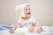 © golovianko - Cute baby in hat with pompom playing with yarn ball