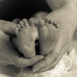 Feet of newborn baby and mother's hands