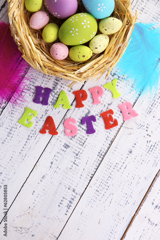 Easter eggs in nest and sign on color wooden background