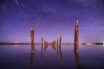 Poles in the water at night on a background star trails