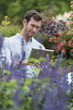 © Mint Images - An organic flower plant nursery. A man working, using a digital tablet.