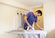 © Mint Images - A man ironing a shirt on the ironing board.