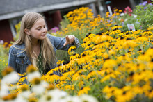 An Organic Flower Plant Nursery. A Young Girl Looking At The Flowers.