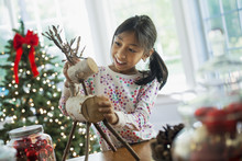 A Young Girl Assembling A Twig Figure Of A Reindeer, Making Christmas Decorations. 
