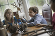 © Mint Images - Three children sitting at a table in family home. A twig reindeer in the centre, with branches and twigs to make objects.