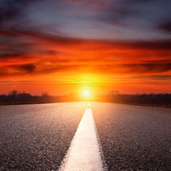 Wall Mural - Driving on an empty asphalt highway towards the setting sun