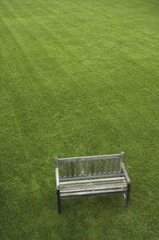 A Wooden Bench On A Grass Lawn.