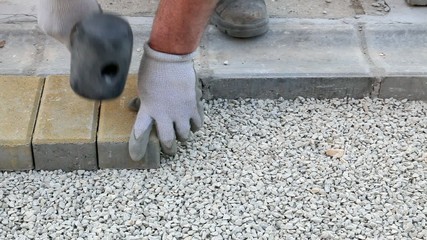 Wall Mural - Worker installing brick paver, using hammer