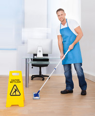 Wall Mural - Warning notice as a janitor mops the floor