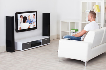 Man sitting on a sofa in his living room watching television