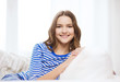 © Syda Productions - smiling teenage girl sitting on sofa at home
