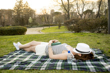Woman Sleeping With A Hat Over Her Face Lying On Grass Park