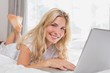 © lightwavemedia - Casual young woman using laptop in bed