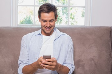 Wall Mural - Casual man reading text message on sofa