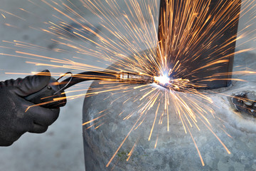 Arc welding of a steel, welder hands in gloves and tool