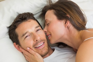  Cheerful young couple lying together in bed