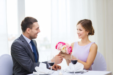 Canvas Print - smiling man giving flower bouquet at restaurant