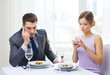 © Syda Productions - busy couple with smartphones at restaurant