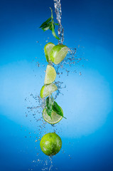 Wall Mural - Pieces of limes in water splash