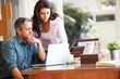 © Monkey Business - Worried Hispanic Couple Using Laptop On Desk At Home