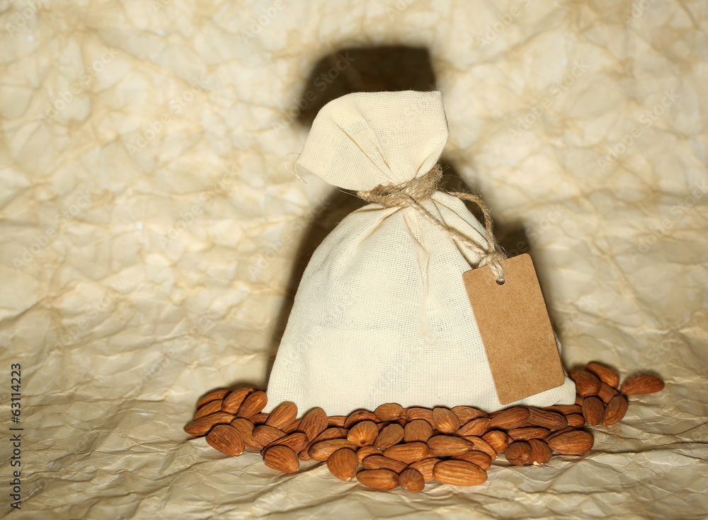 Almonds in sack with tag on old paper background