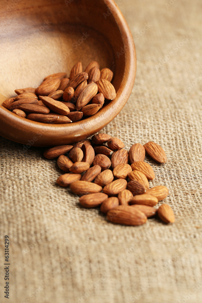 Almonds in bowl on sackcloth background
