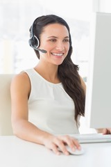 Sticker - Smiling call centre agent sitting at her desk on a call